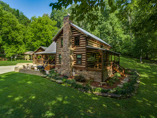Traditional two story cabin with a non traditional porch system wrapping then entire home, stone two-story fireplace and metal roof