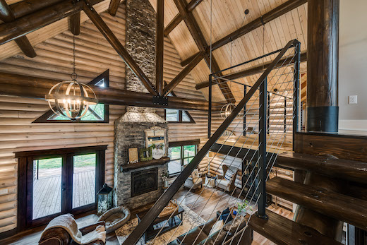 photo of interior of a timbercraft home with traditional wood walls and ceiling and open floor plan with steel stairs and exposed wood beams with steel supports